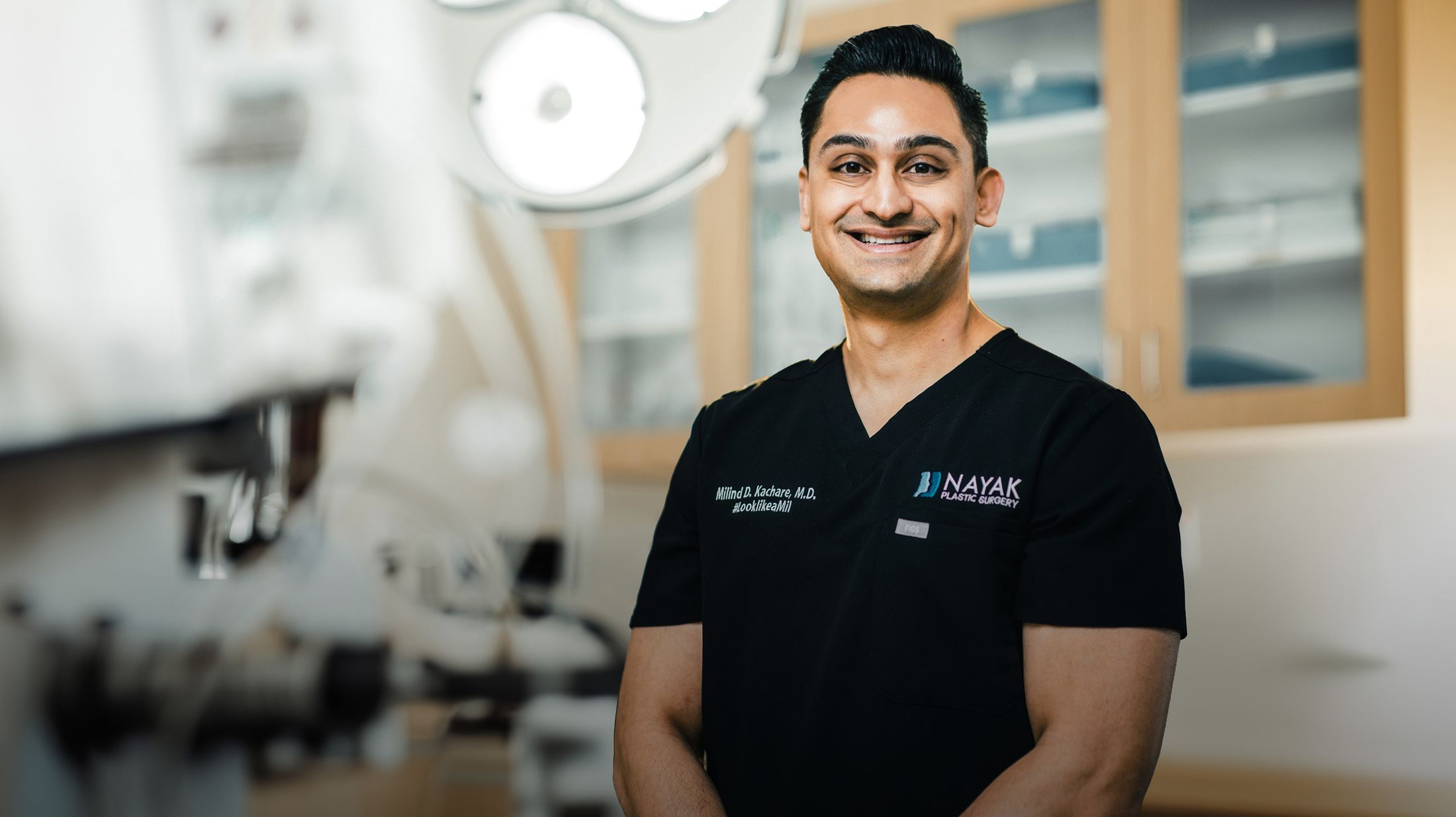 Dr. Kachare in scrubs smiling in a medical office.