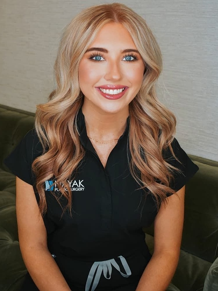 Smiling professional in beauty clinic attire.