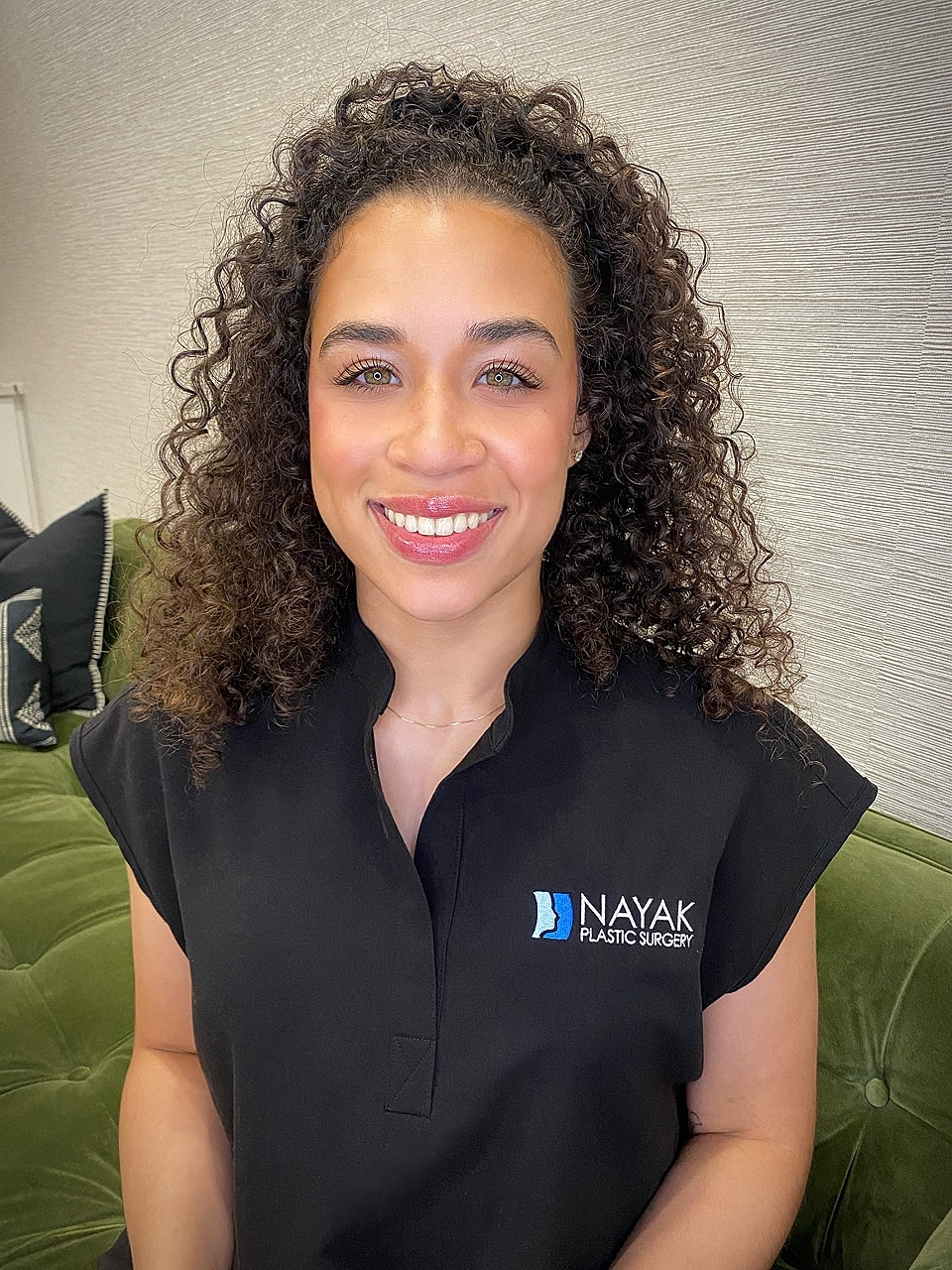 Smiling woman in plastic surgery office setting.