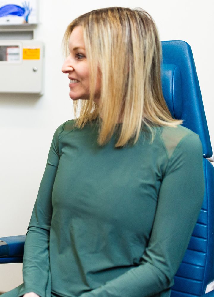 Smiling woman in green attire sitting in office.