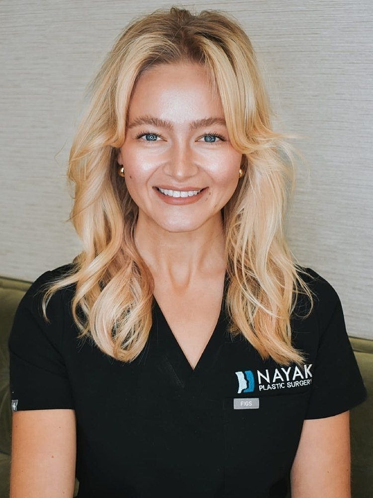 Smiling woman in medical attire, plastic surgery office.