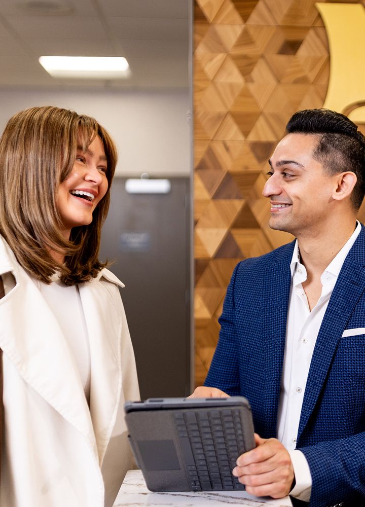 Two professionals smiling and engaging over a tablet.