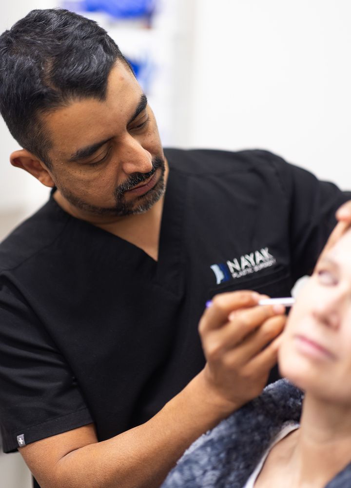 Professional applying treatment on patient’s face.