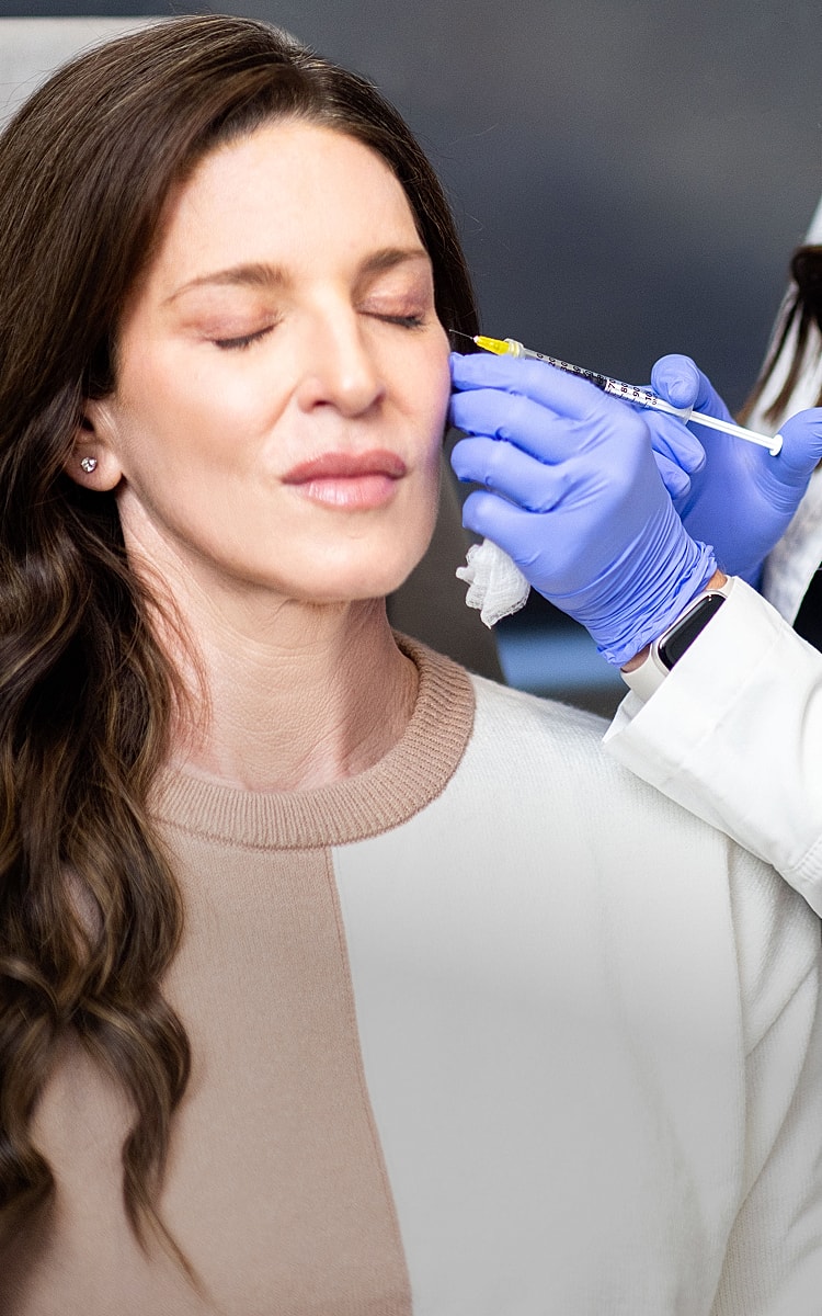 Woman receiving facial treatment with syringe.