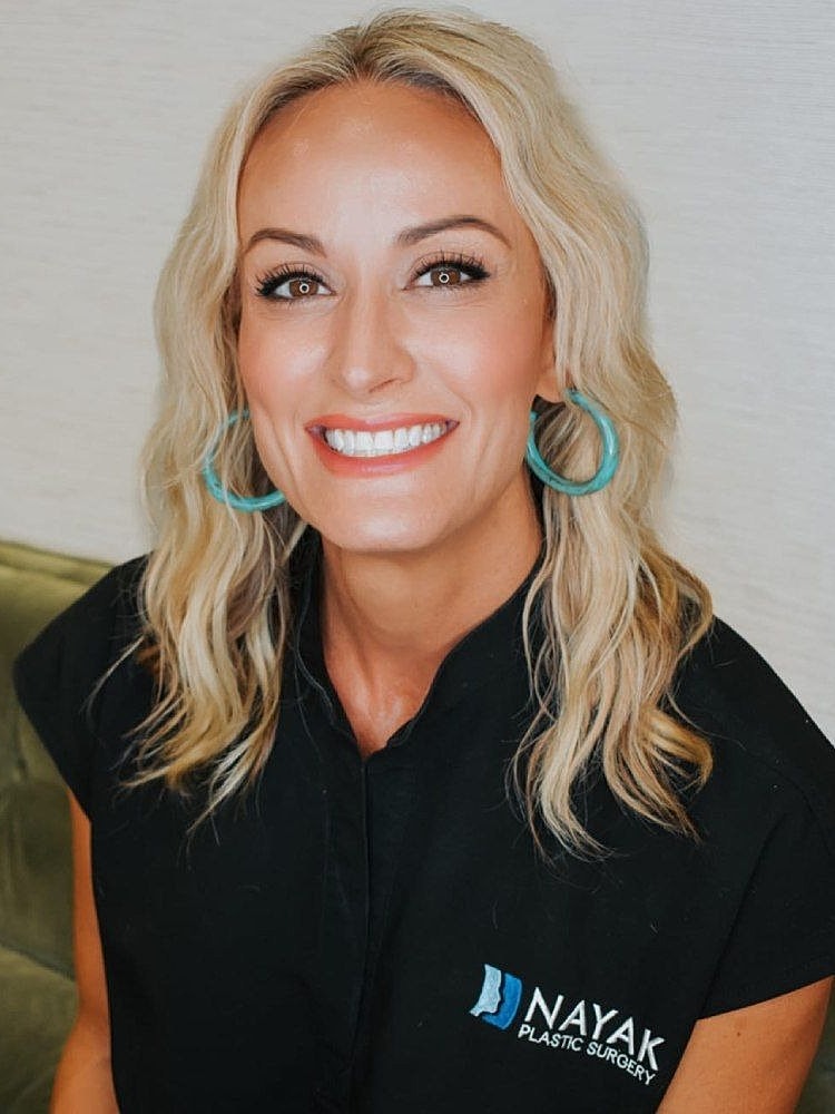 Smiling woman in medical attire at plastic surgery clinic