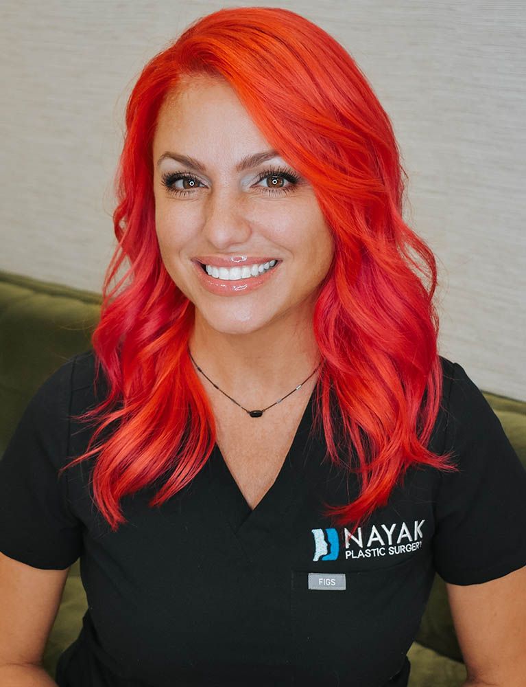 Smiling person with vibrant red hair in scrubs.