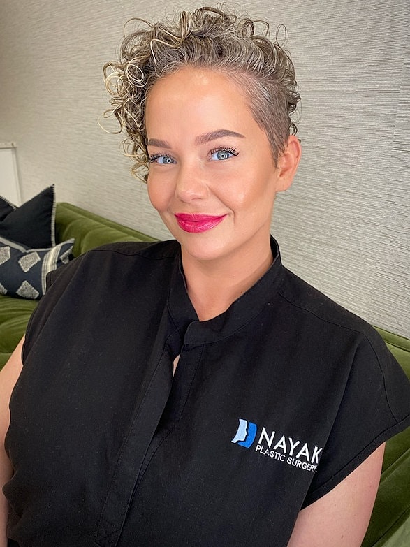 Woman with curly hair smiling in uniform.