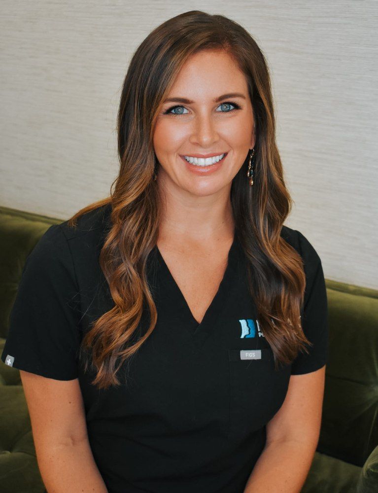 Smiling woman in medical scrubs, sitting indoors.