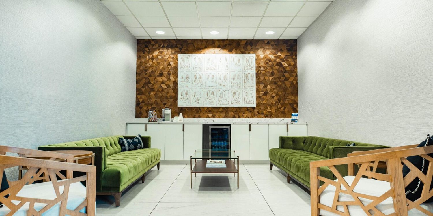 Modern waiting area with green sofas and art.