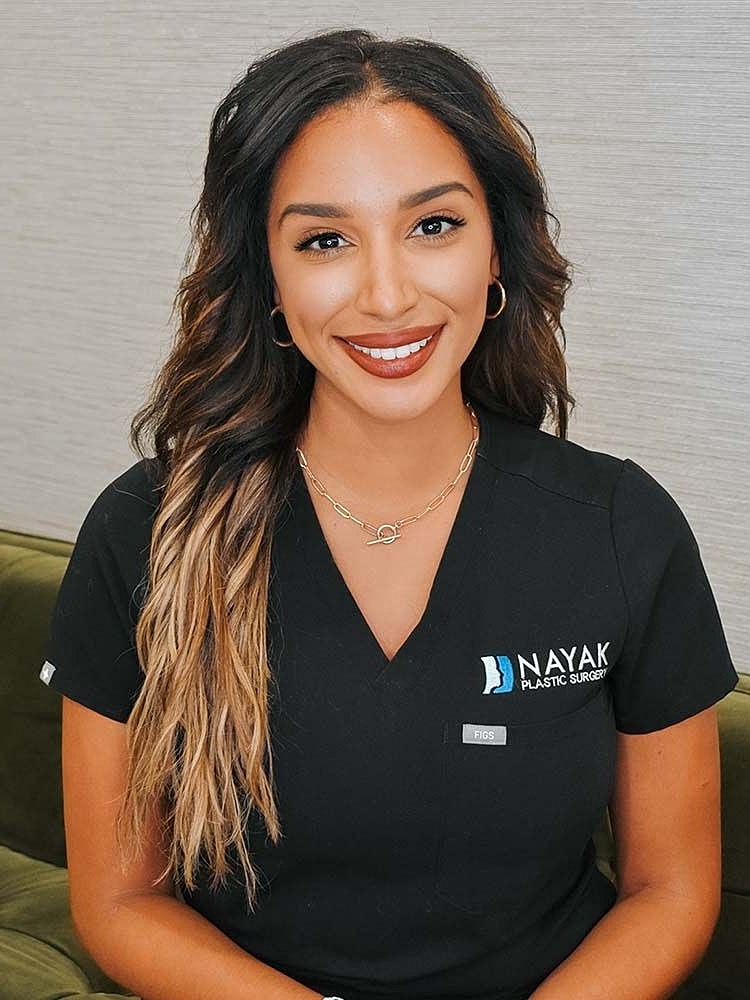 Smiling woman in medical scrubs, professional setting.