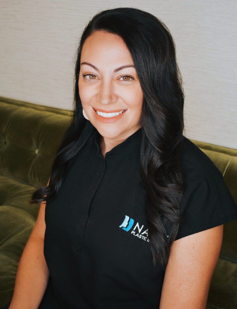 Woman smiling in black shirt against green background.