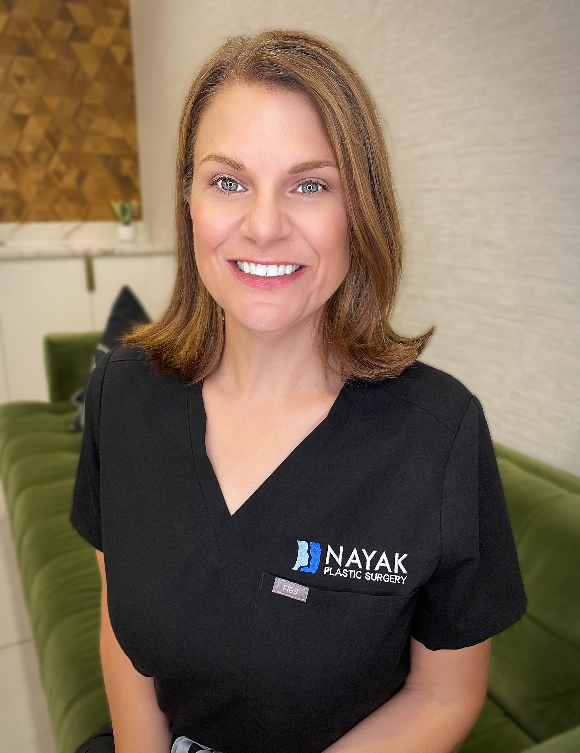 Woman smiling in medical scrubs at clinic.