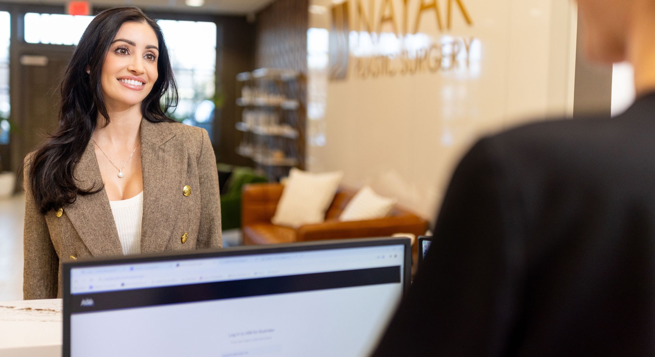 Smiling woman at a plastic surgery consultation desk.