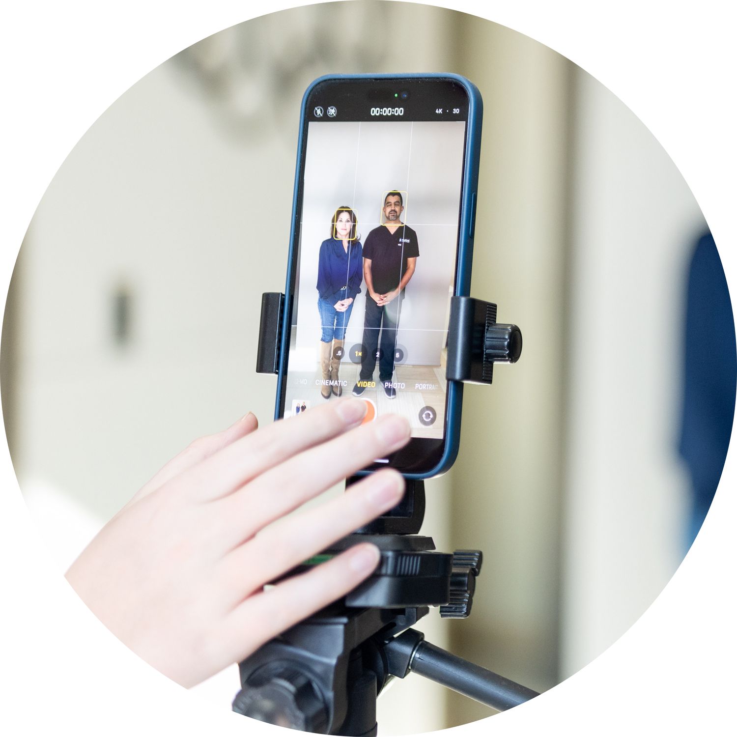 Smartphone on tripod capturing video of two people.
